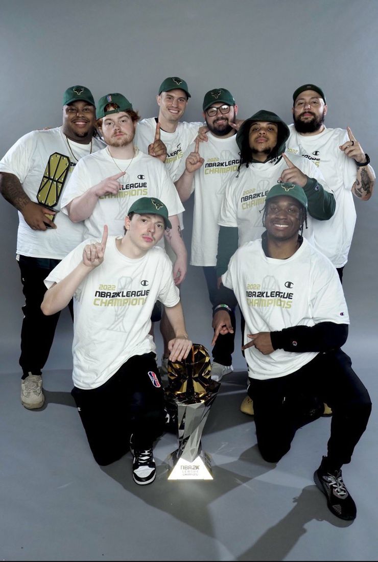 Bucks Gaming players and staff in 2022 NBA 2K League Champions shirts around the trophy